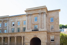 Exterior of the top three storeys of a sandstone building with columns set into the wall.
