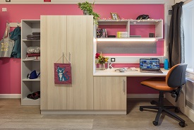 A desk with an office chair nearby, shelves above it and a cupboard next to it.