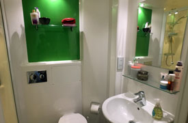 A bathroom with a toilet, sink, mirror and shower cubicle.