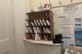 Pigeon holes with letters and mail in boxes with a notice board to the right.