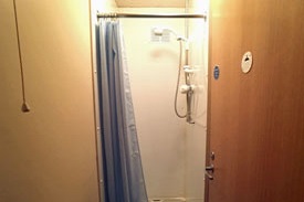 A room with a shower cubicle with a curtain.
