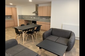 A kitchen and dining room with worktops, cupboards, dining table and chairs, sofas and coffee table