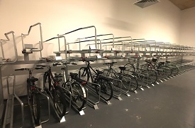 A large room with a long two-level bike storage rack, with several bikes attached to it.