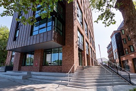 The exterior of a modern multi-storey buidling, with a set of ten steps with handrails leading up to the building entrace.