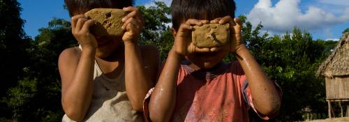 Two children playing with cameras made of clay in Amazonia.