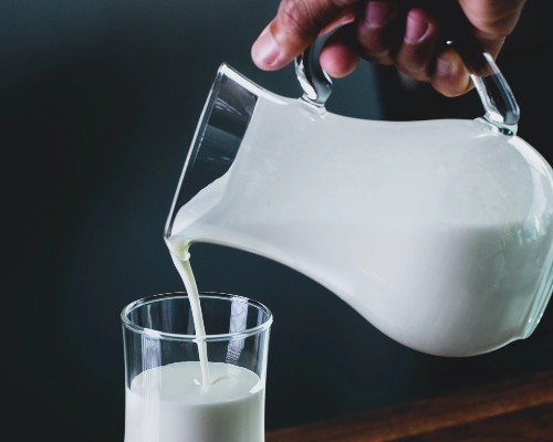 Generic image of a person pouring milk from a jug into a glass.