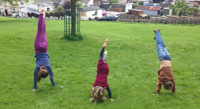 Three children doing handstands in park