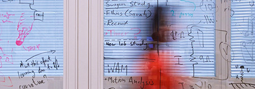 Woman walking along a corridor with maths equations on window