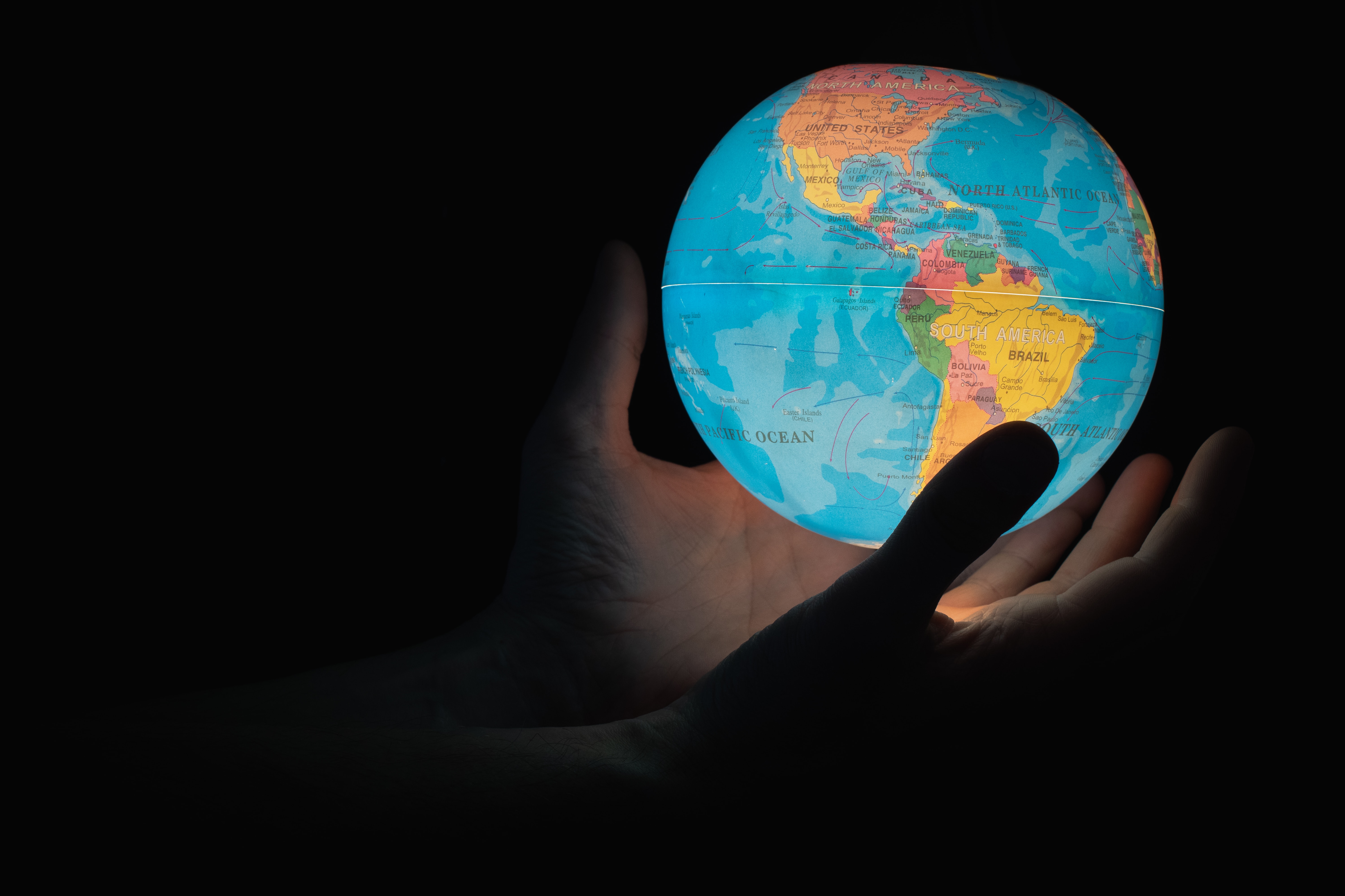 An image of a glowing globe which is being held by two hands. 