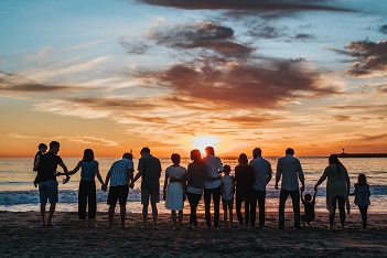Families standing together on a beach looking at the sunset