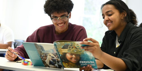 Two summer school students reading a book about Carnival.