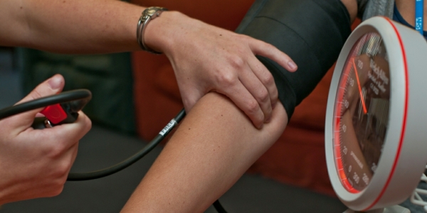 A woman applying a blood pressure measuring device to another woman's arm.