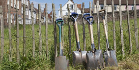 Five shovels leaning against a fence