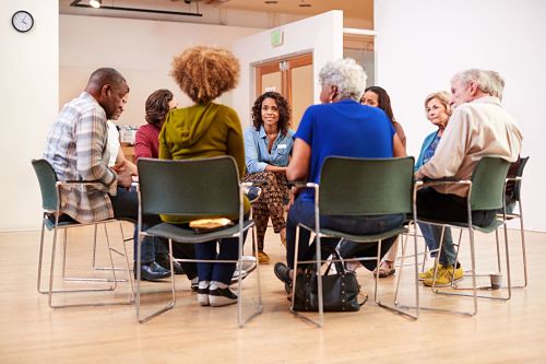 An image of a group of people sat on chairs in a circle having a discussion