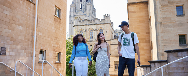 Three students walking through campus with Wills Memorial Building in the background.
