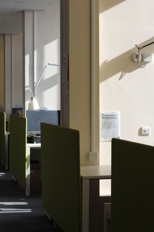 Two entrances of Postgraduate Window Seat study spaces, both include desks, computers and lamps. Well lit by the sun. 