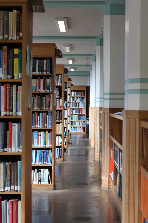 Looking down a corridor which is lined with bookcases full of books. 