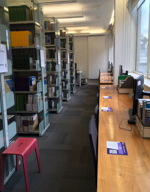 View of computers and bookcases in front of a window.