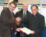 Professor Alan Champneys (left), presents one of the representative of the North Korean government with a copy of the University's centenary book, with Glyn Ford MEP (centre)