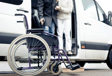 Image of a person being helped out of a bus into a wheelchair