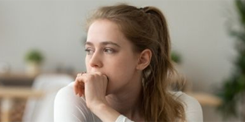 A young white woman looking thoughtful or anxious.