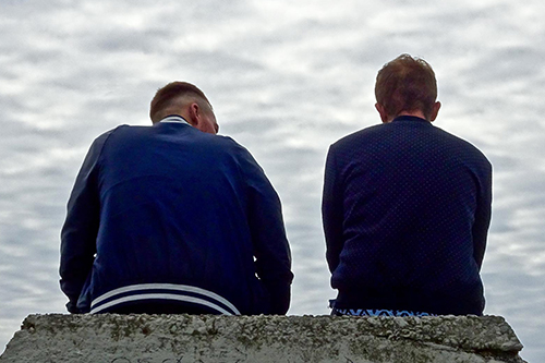 Two men sat on a wall