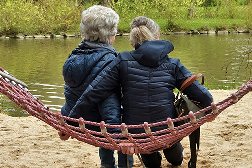 An older and younger woman sat by a lake