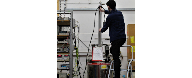 Research student operating Low-consumption Liquid-helium cryostat