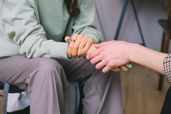 Close-up of person holding hand of another in a gesture of comfort/support.