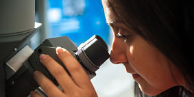 Image of female student looking into a microscope 