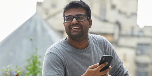 A student relaxing on campus, holding their mobile phone