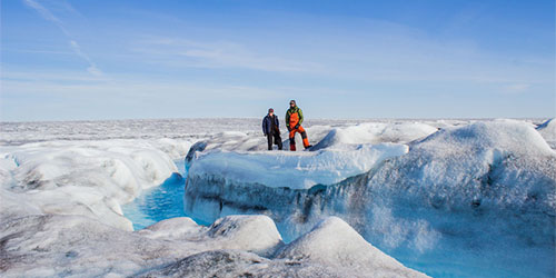 2 researchers standing on a glacier. 