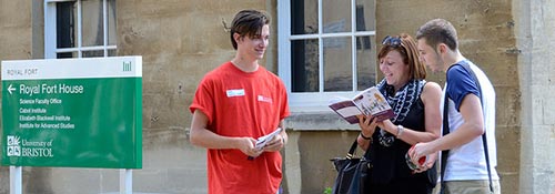 Student ambassador outside a university building helping visitors find where they need to go at an open day.