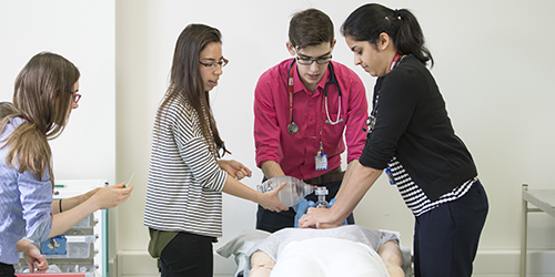 Three people performing CPR on a dummy.