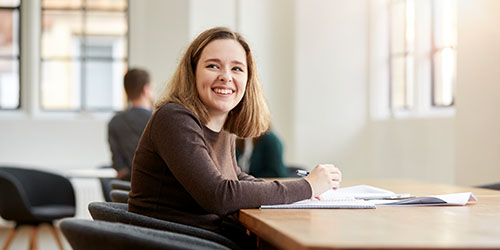 Student smiling and sitting at a desk studying.