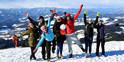 Group of people with arms raised on a snowy mountain.