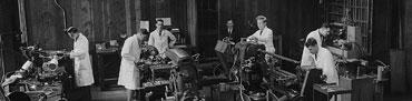 An old black and white photograph of staff in lab coats working in the old physics workshop.