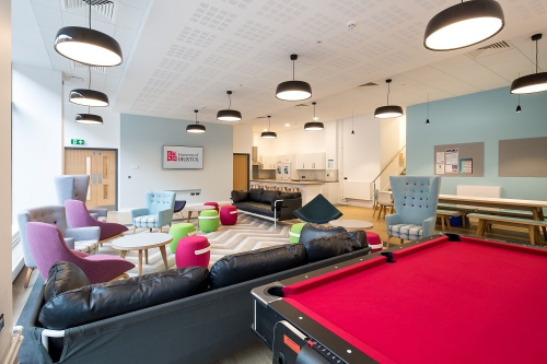 Inside a hall of residence communal area with sofas and a pool table