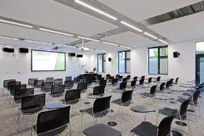 A spacious modern room with rows of desks and a projector screen
