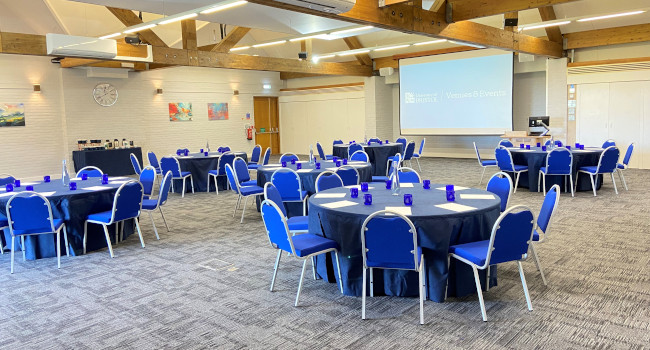 Wills Hall Conference Centre setup for a meeting with round tables and a projection screen