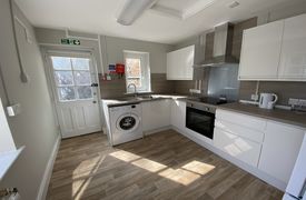 A kitchen with an oven and hob, a sink, a washing machine and several cupboards and drawers.