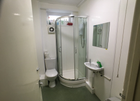 A bathroom with a toilet, shower cubicle, sink and mirror.