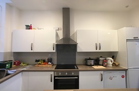 A kitchen with an oven and hob, several cupboards and a fridge freezer.