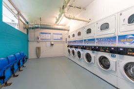 A laundry room with six washing machines and tumble dryers.