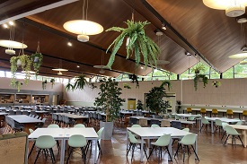 A large dining hall with tables and chairs around each of them.