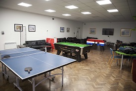 A room with a table tennis table in the foreground and pool table and table football in the background.