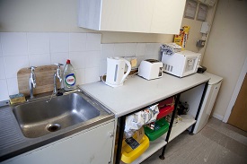 A small pantry area with facilities to heat up food, including a microwave, toaster and kettle. Cupboards and fridge to store food. Sink and recycling facilities too.