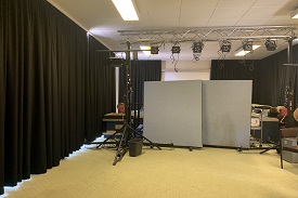 A room with curtains along each wall and a lighting rig and other theatre equpiment in the centre.