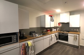 A kitchen with an oven and hob, a sink, a microwave, and lots of cupboards and drawers.