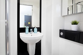 A bathroom with a sink with a mirror above it, and a medicine cabinet with mirrored doors on a wall nearby.